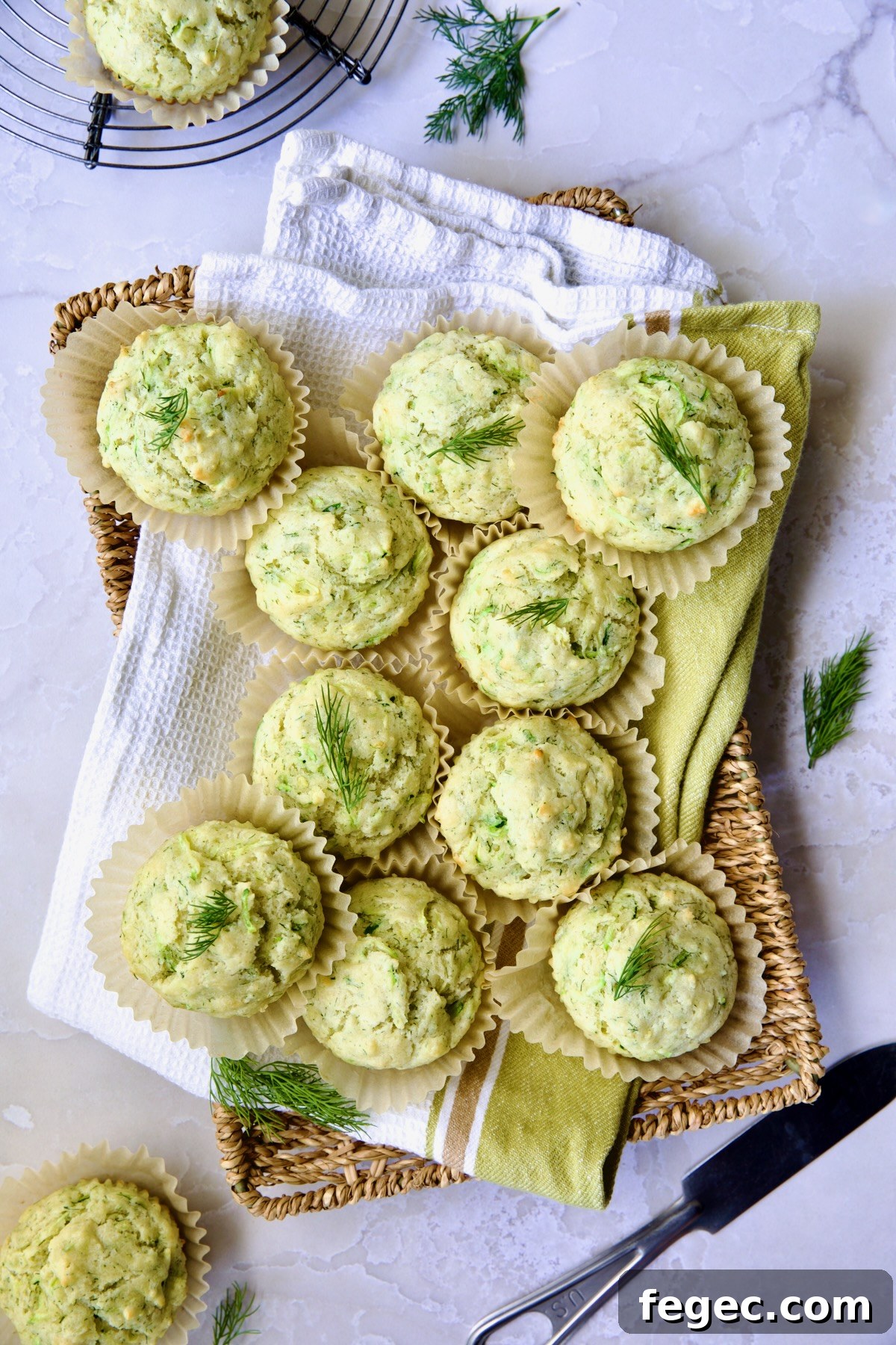 Pile of Dill Zucchini and Ricotta Muffins on square rattan basket.