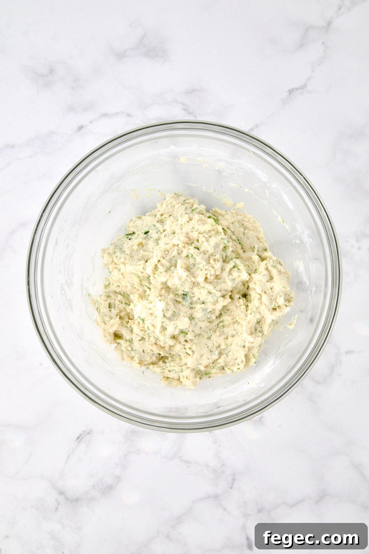 Wet and dry ingredients for muffins combined in glass bowl.