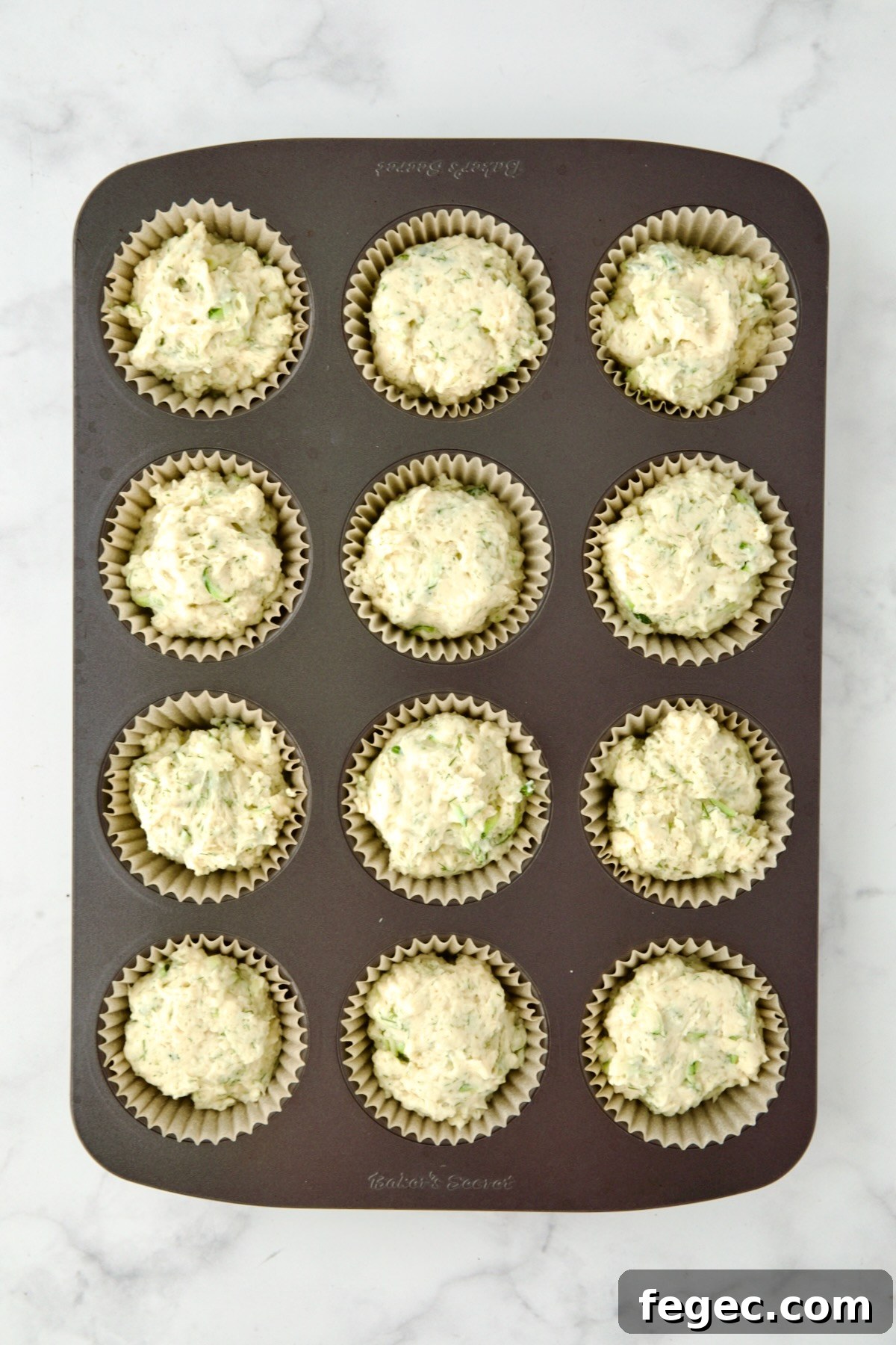 Batter for muffins divided into 12 paper-lined muffin cups.