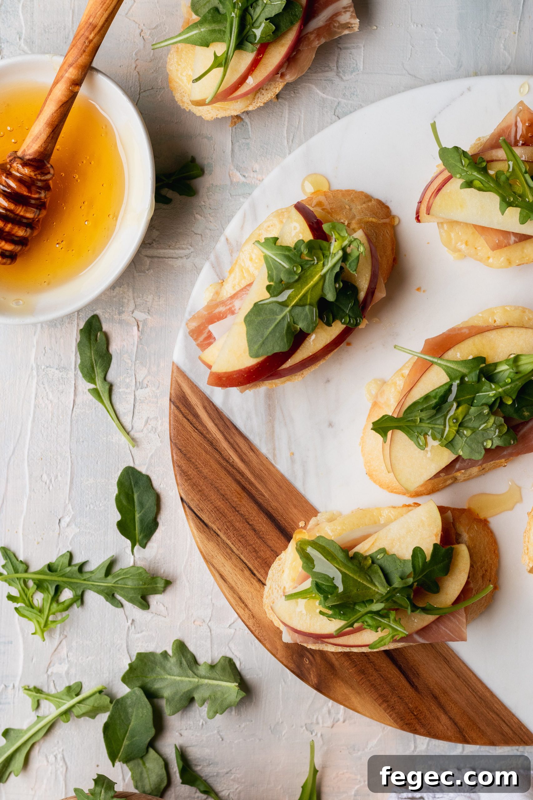White Cheddar + apple crostini with arugula, prosciutto, and honey