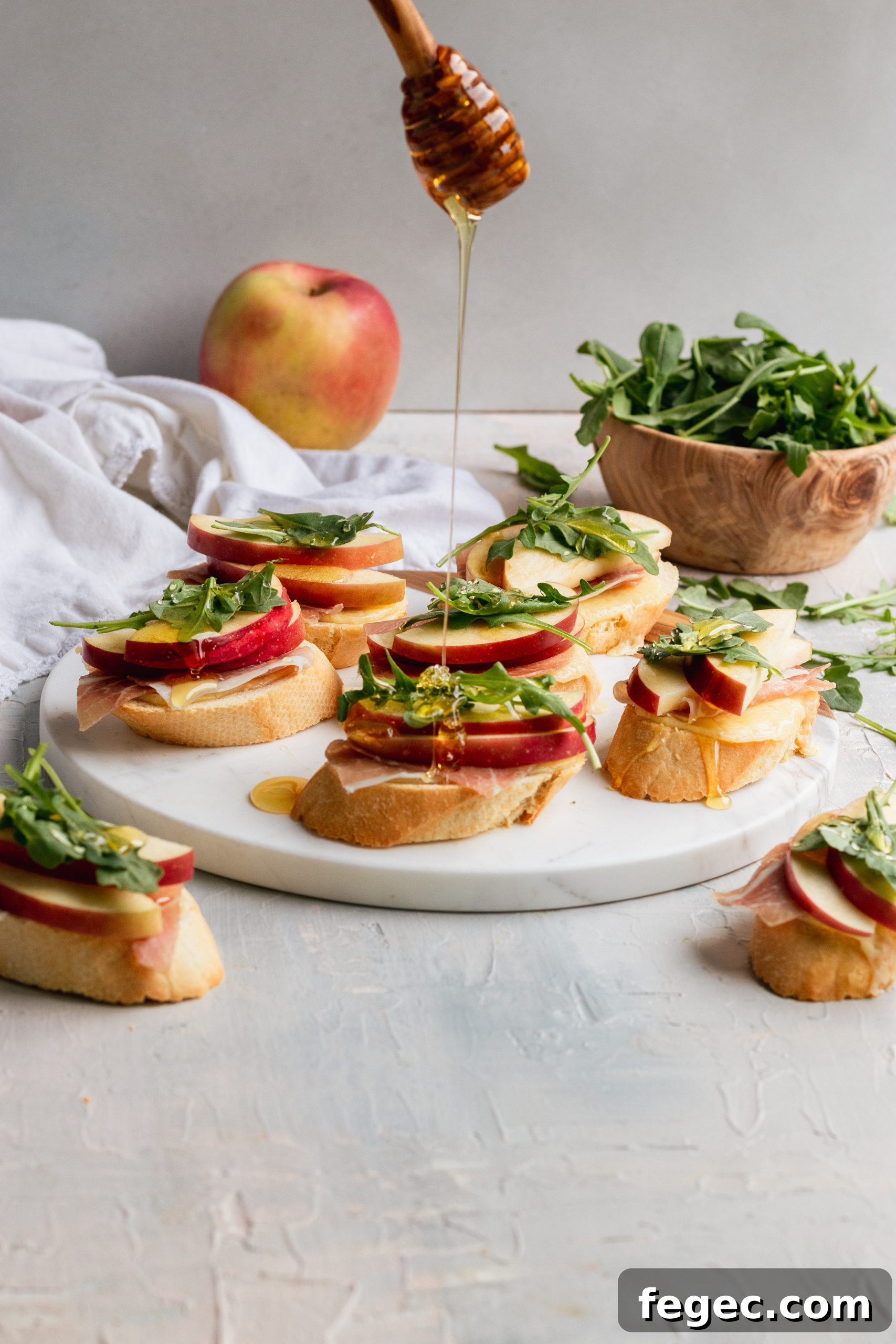 White Cheddar + apple crostini with arugula, prosciutto, and honey