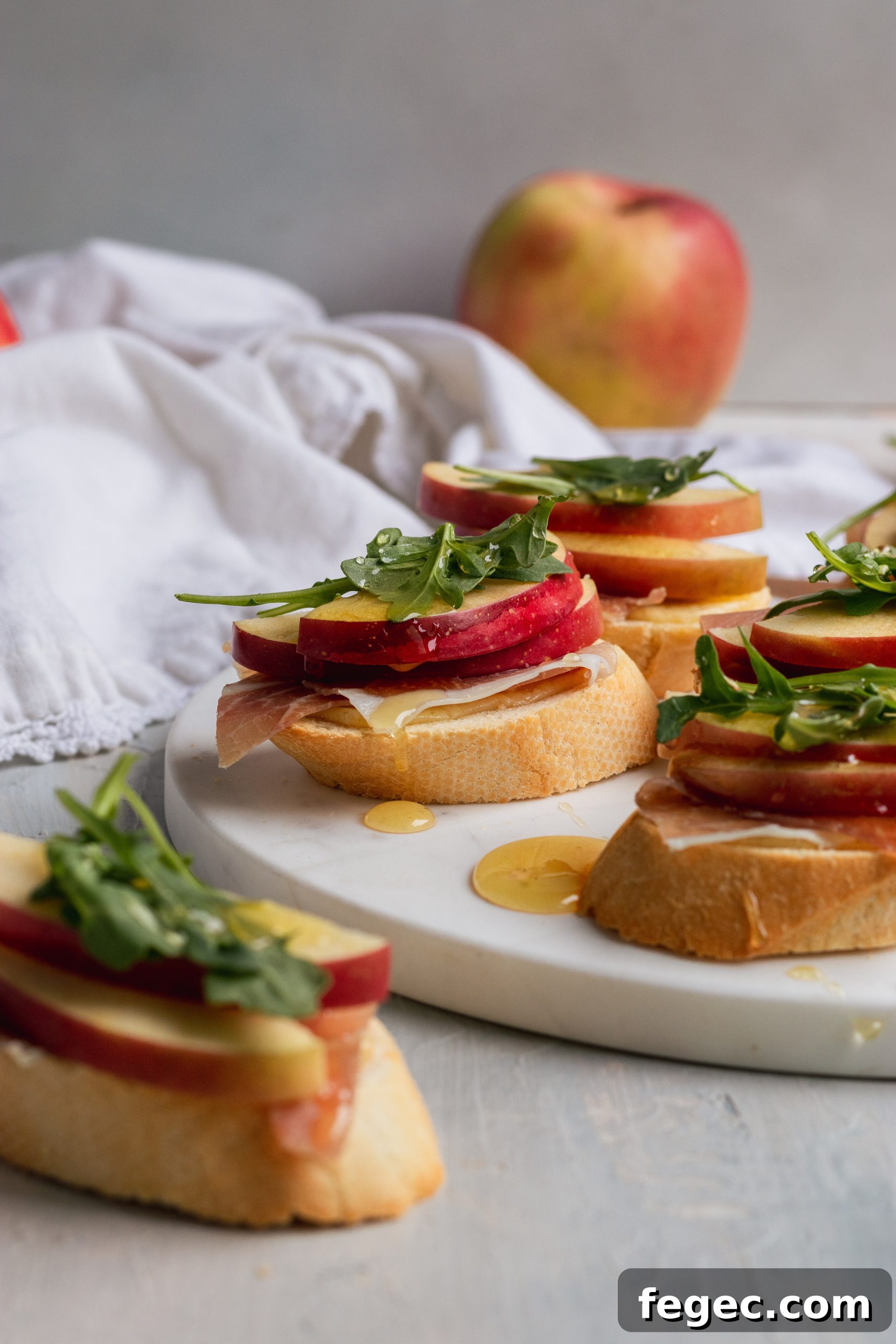 White Cheddar + apple crostini with arugula, prosciutto, and honey