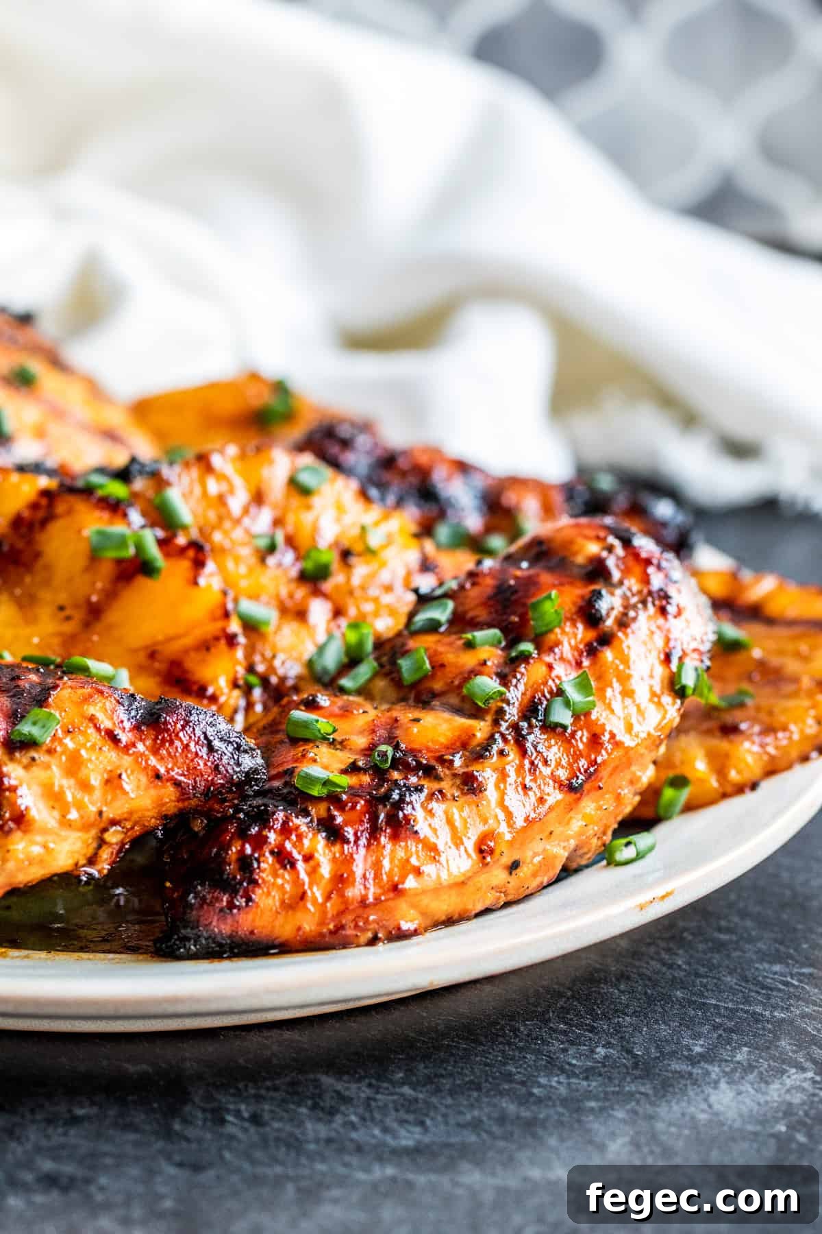 Shot of grilled chicken on white platter with gray counter.