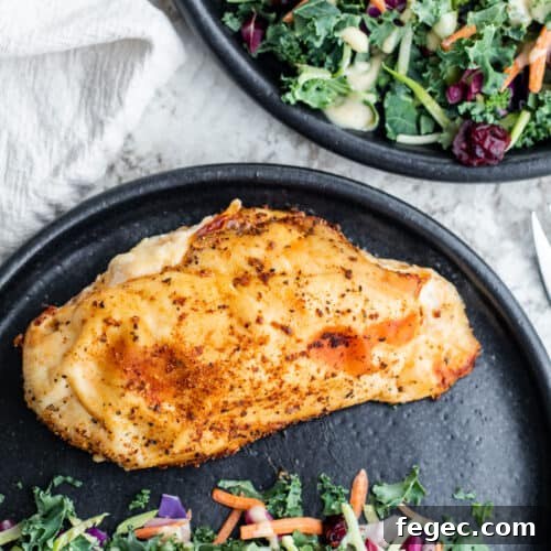Overhead shot of chicken on black plate with side salad.