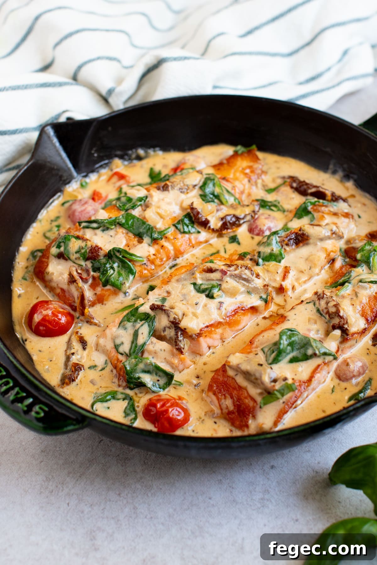 Tuscan salmon dinner recipe in a skillet on a white countertop ready for serving.