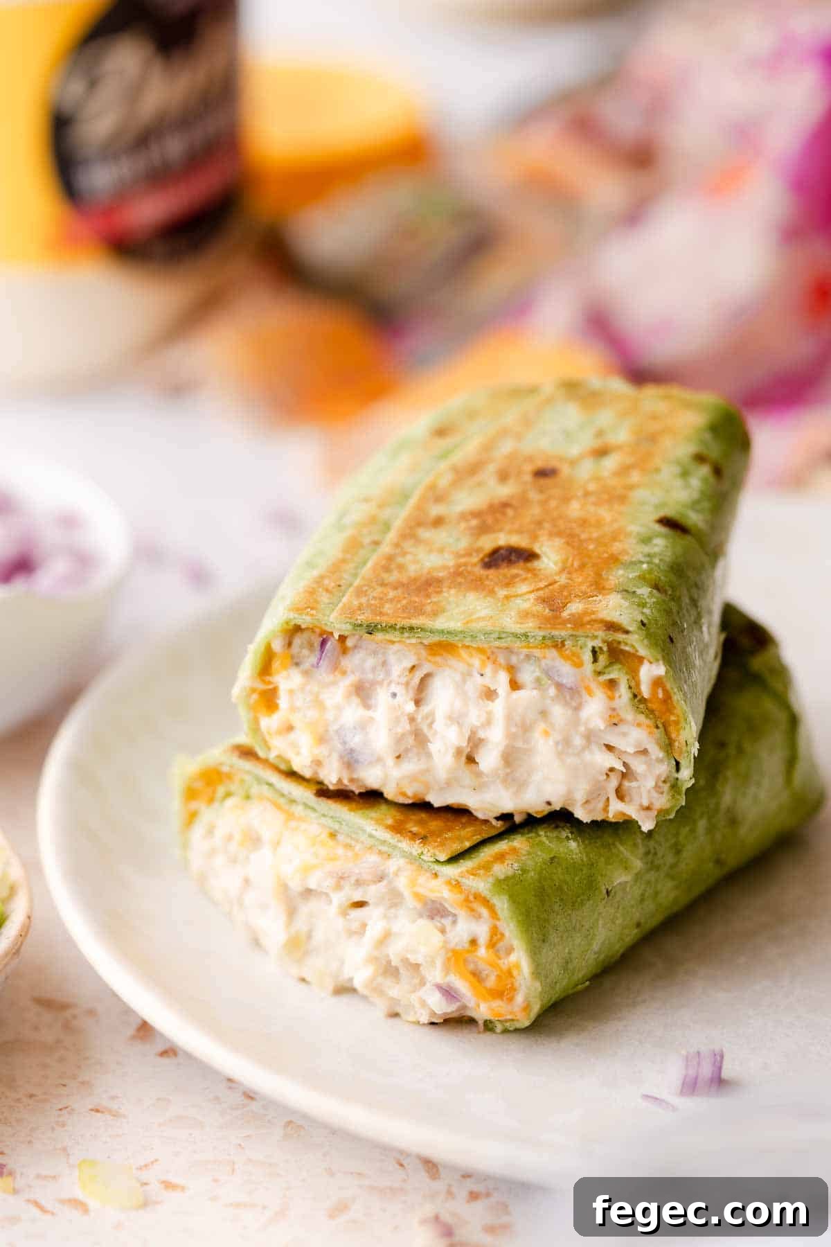 Crispy Tuna Melt Wrap Recipe for Quick Lunch or Picnic 2 tuna wrap cut in half stacked on white plate.