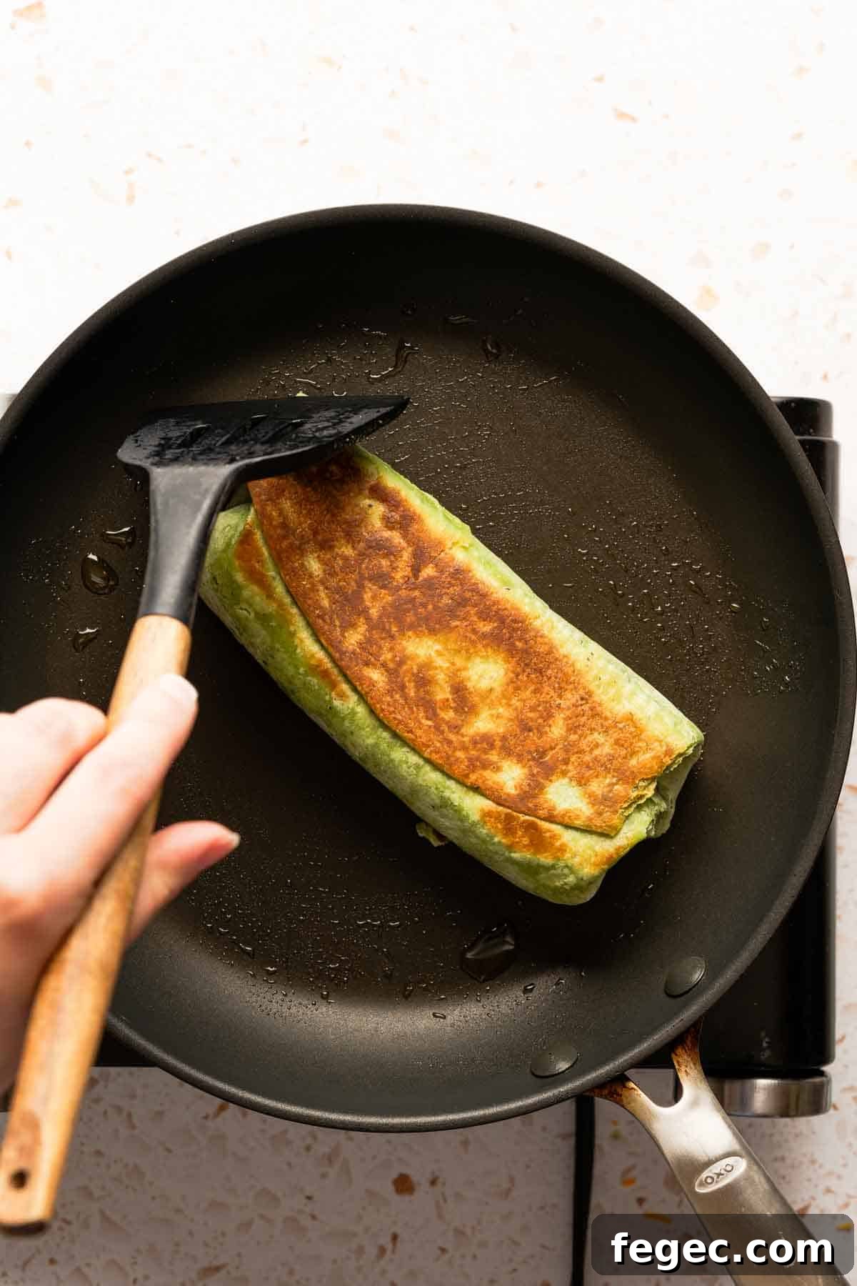 Crispy Tuna Melt Wrap Recipe for Quick Lunch or Picnic 14 browned tortilla wrap in skillet with spatula.