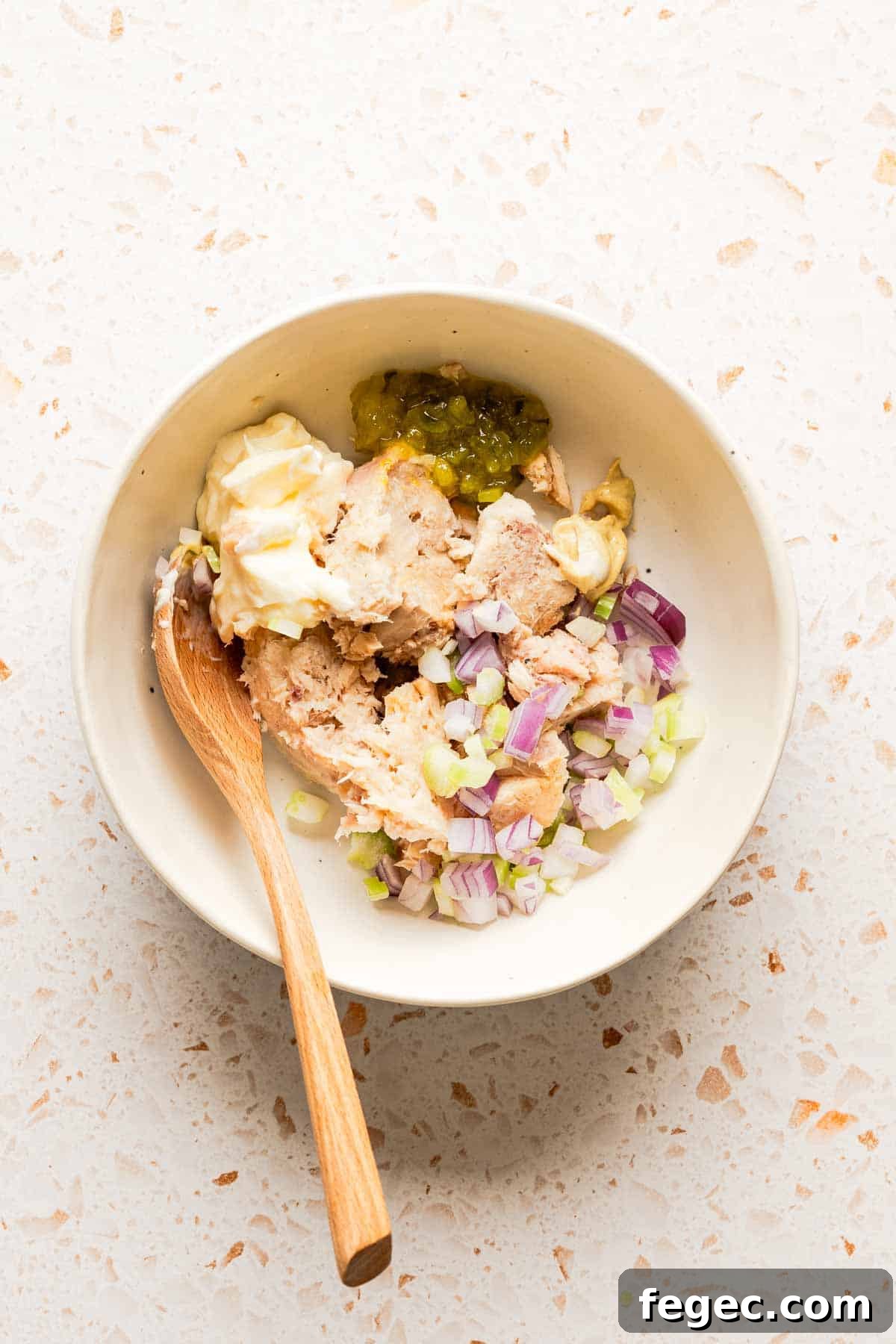 Crispy Tuna Melt Wrap Recipe for Quick Lunch or Picnic 4 ingredients for tuna salad in bowl with wooden spoon.
