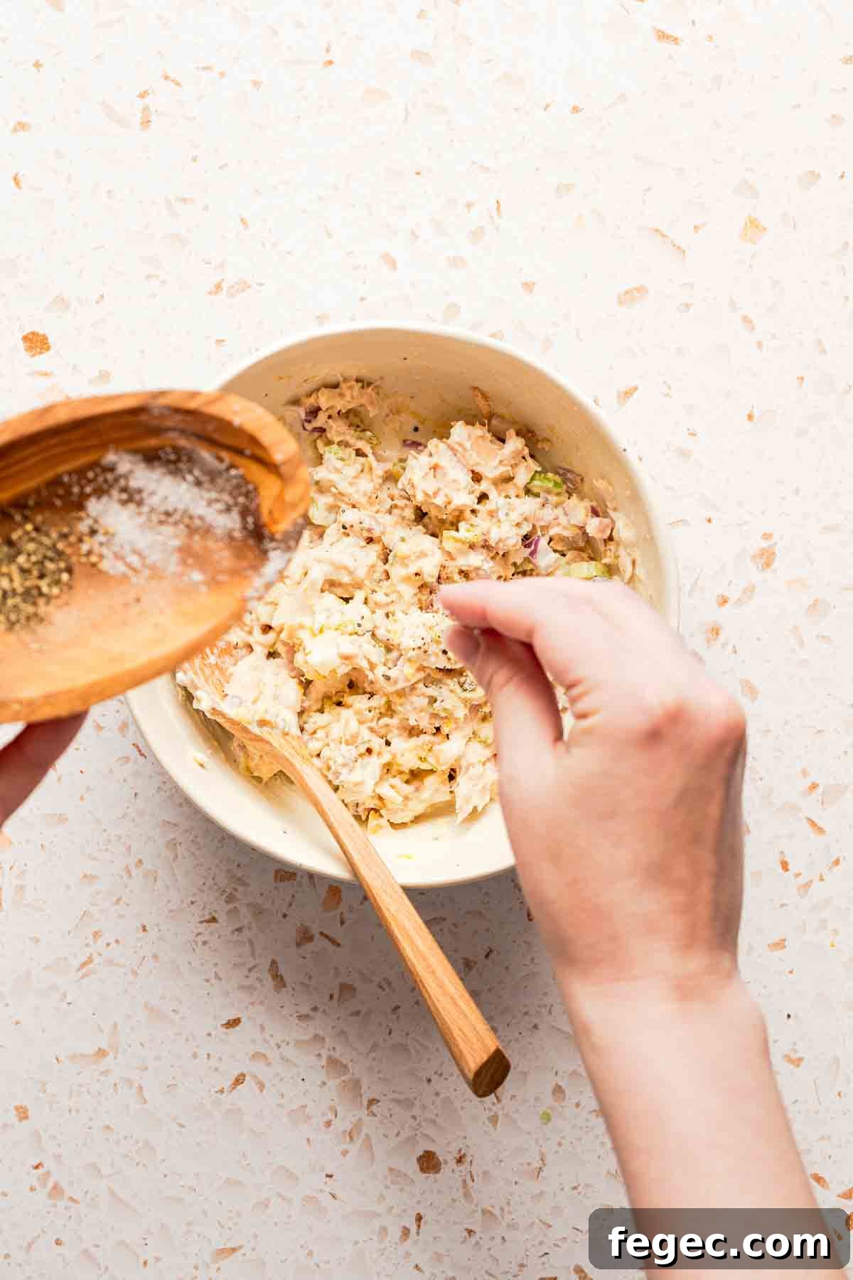 Crispy Tuna Melt Wrap Recipe for Quick Lunch or Picnic 6 hand sprinkling salt into bowl of tuna salad.