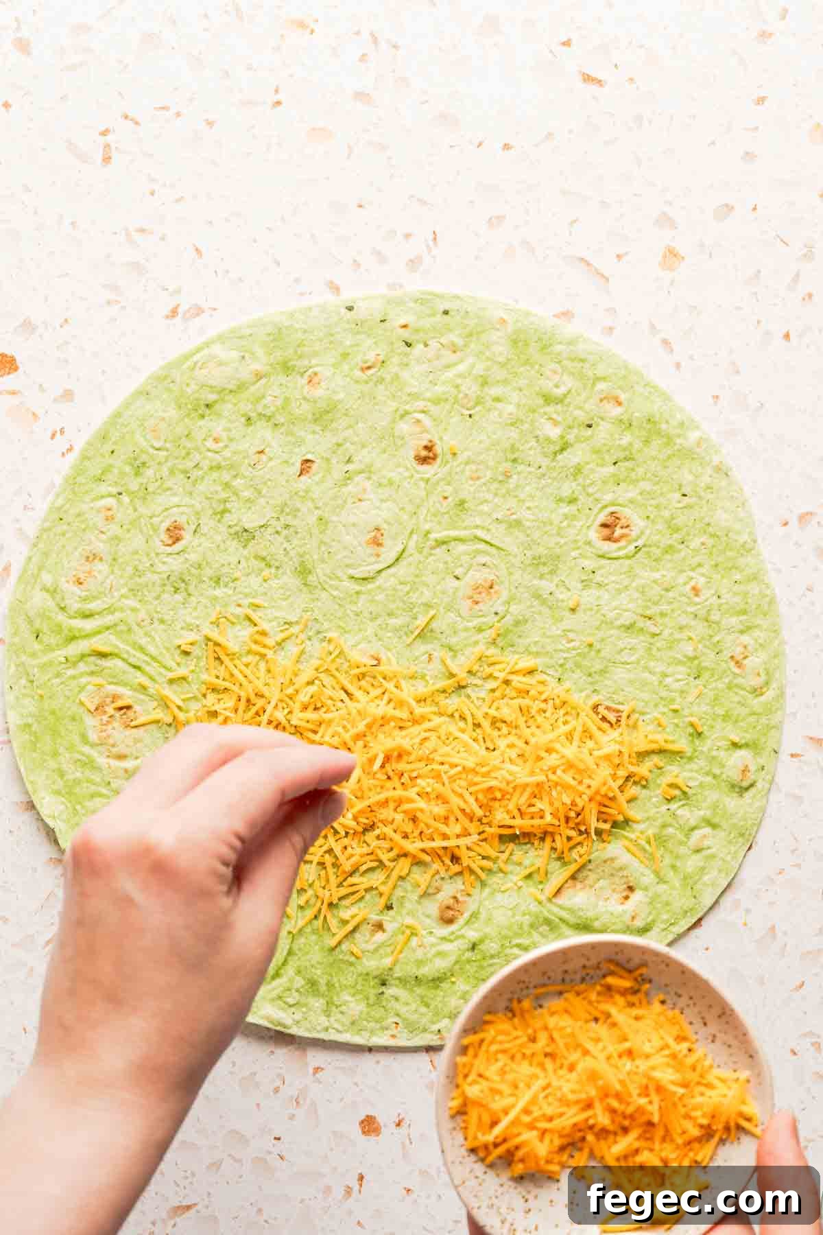 Crispy Tuna Melt Wrap Recipe for Quick Lunch or Picnic 7 shredded cheese being sprinkled on half of tortilla.
