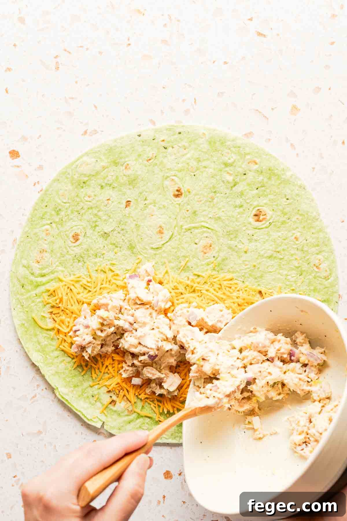 Crispy Tuna Melt Wrap Recipe for Quick Lunch or Picnic 8 tuna salad being placed on tortilla with cheese.