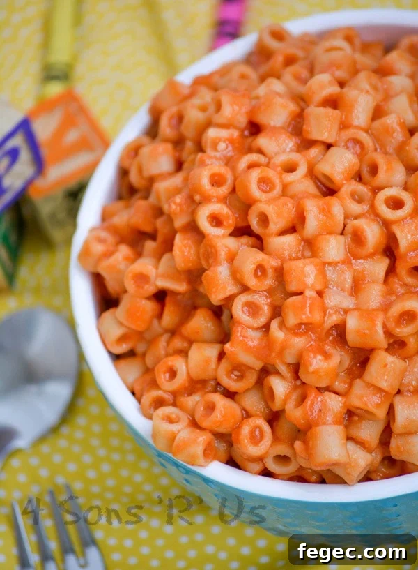 Homemade Spaghetti O's in a white rimmed blue bowl on a yellow background