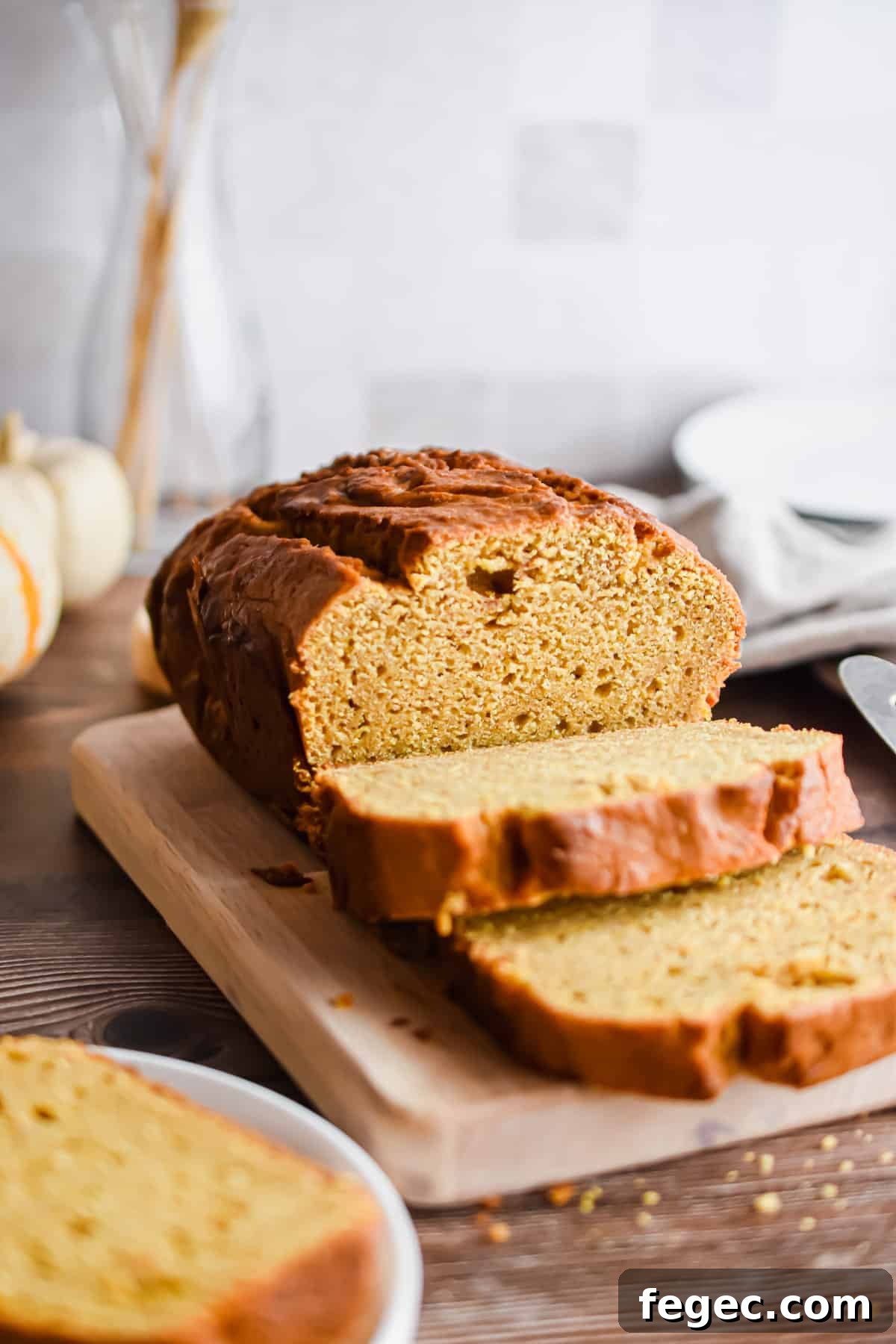 The pumpkin bread is on a cutting board and some slices are cut.