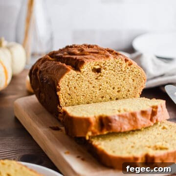 The pumpkin bread is on a cutting board and some slices are cut.