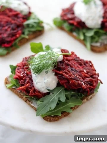 An open sandwich with beet and celery root cakes and creamy sauce on a plate