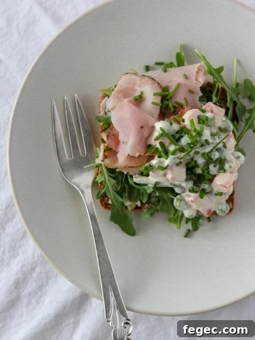 An open ham sandwich on a plate with a fork