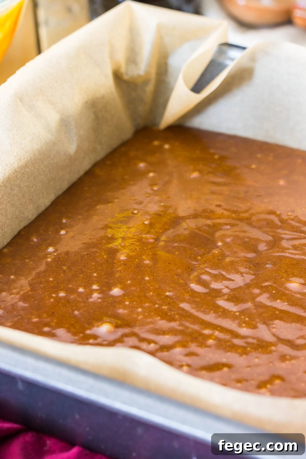 Gingerbread cake batter in metal pan that's been lined with parchment paper