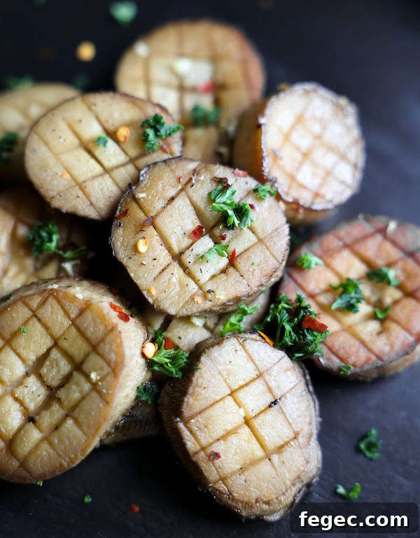 An angled close-up shot of vegan scallops on on a black platte, garnished with chopped parsley.