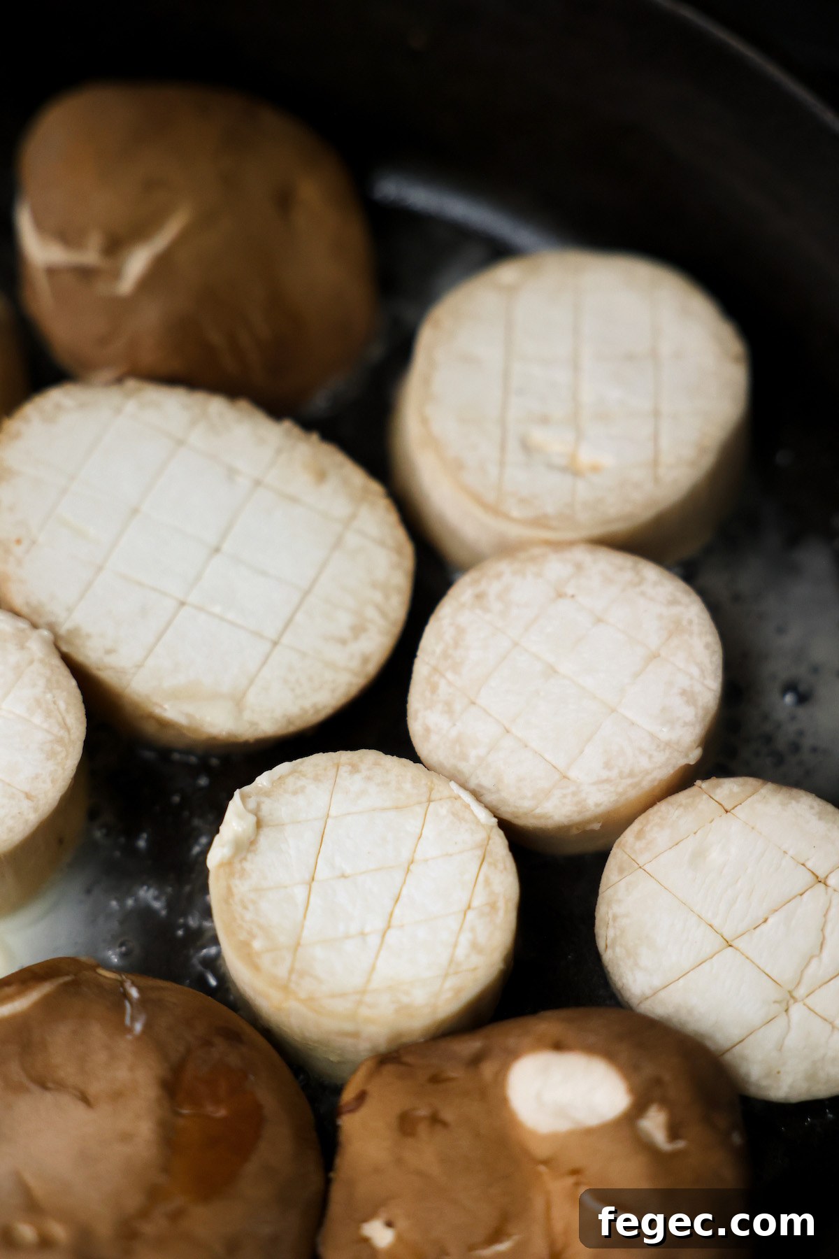 Raw king oyster mushrooms in a skillet with vegan butter.