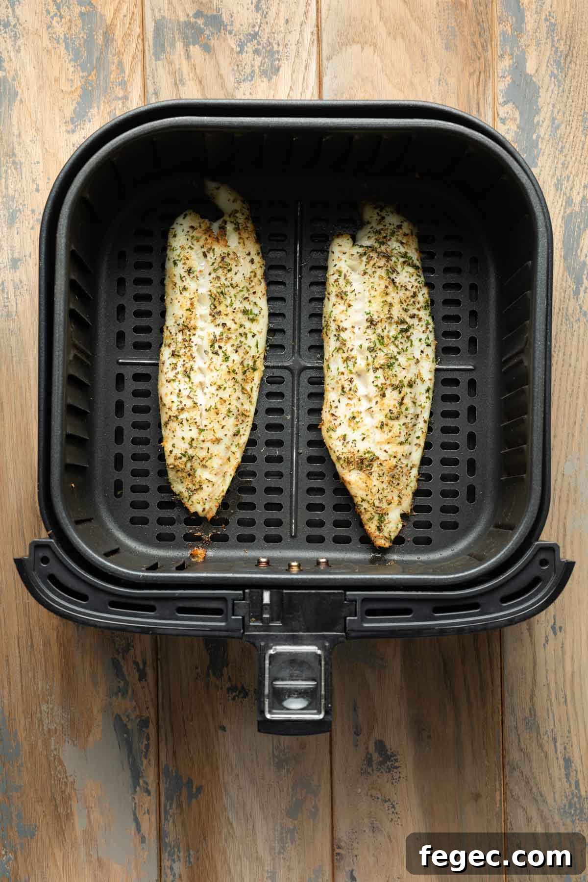 Air fried tilapia loins in an air fryer basket.