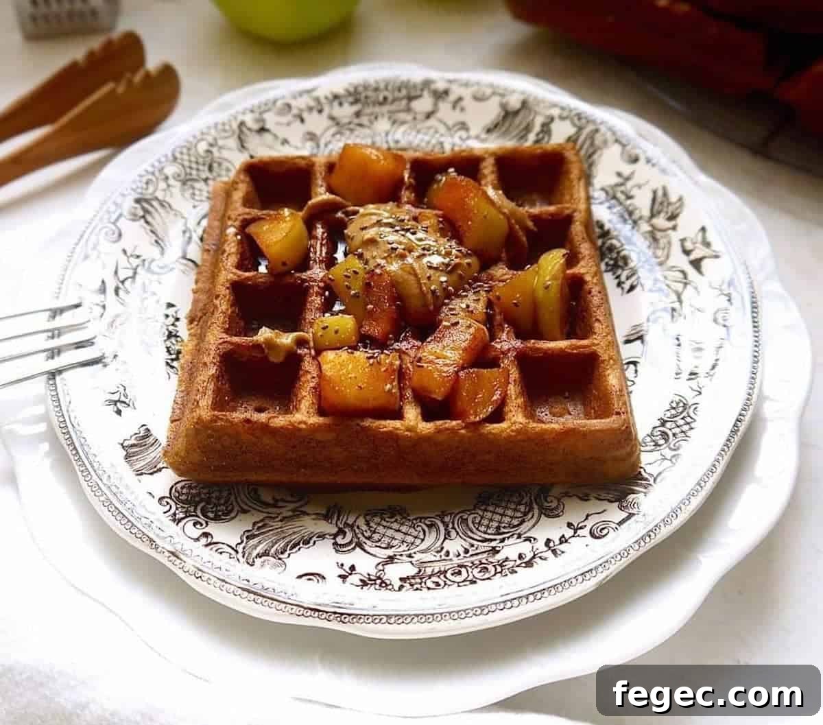 Paleo apple cinnamon waffles on a plate with apples on top.