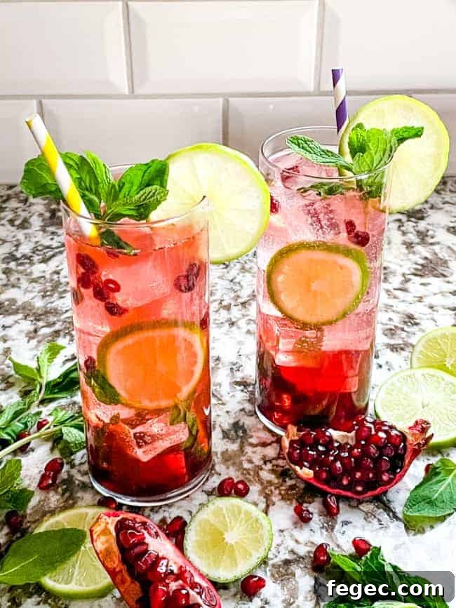 A couple red pomegranate mojitos garnished with lime and mint.