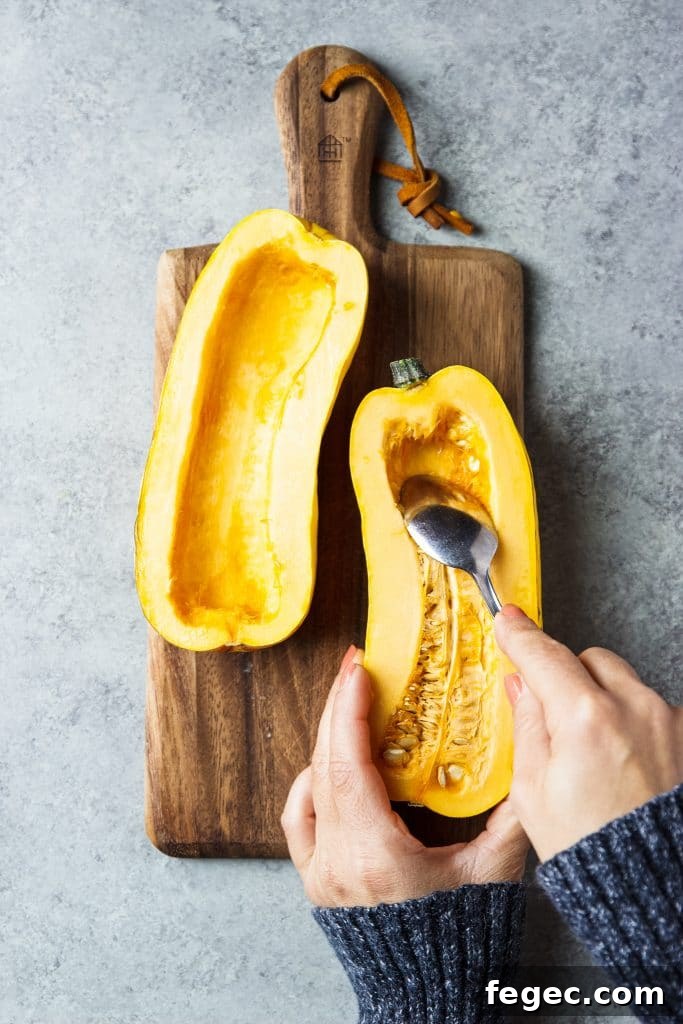 delicata squash being cleaned with a spoon removing seeds.