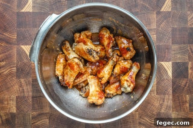 Tossing hot honey chicken wings with the hot sauce, butter, and lime zest.