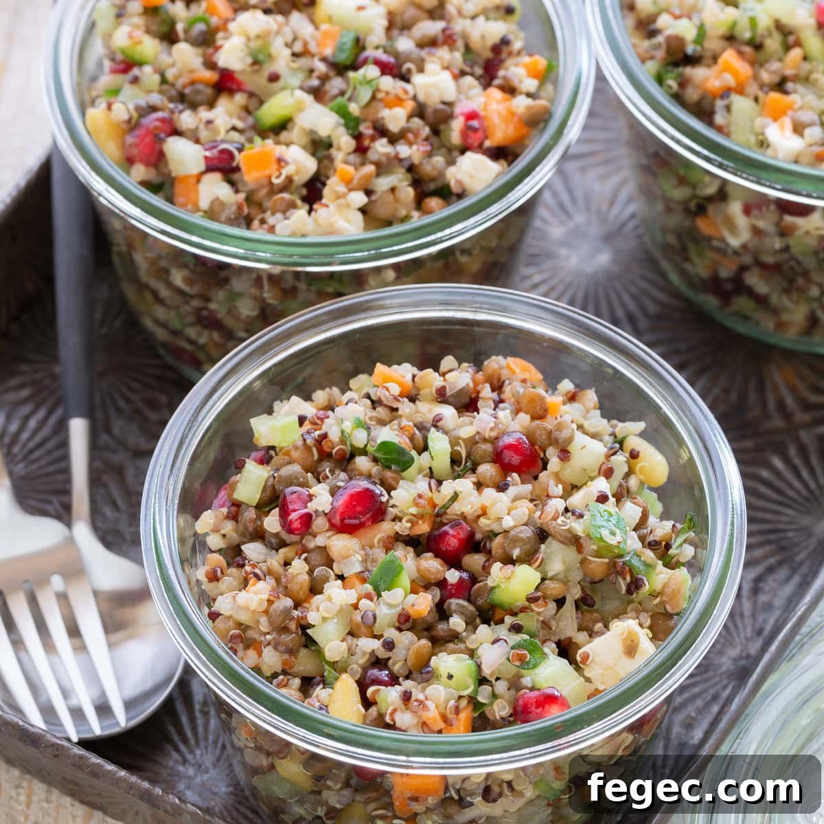 Brightly colored lentil salad in glass jars on a tray with forks.