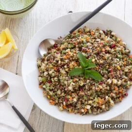A white bowl of lentil quinoa salad with basil leaves and a serving spoon.