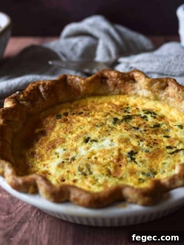 Angled view of tomato, leek and feta quiche on a brown surface.