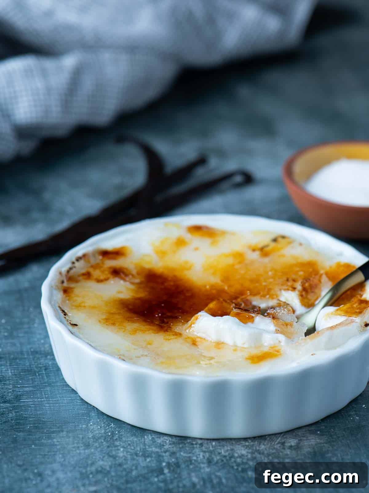Vanilla yogurt brulee in a white ramekin with a spoon.