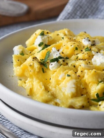 Close-up of goat cheese-scrambled eggs on a white plate.