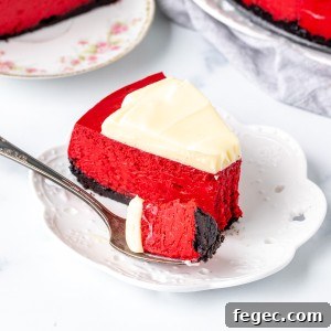 Piece of red cheesecake with cream cheese frosting and an Oreo crust