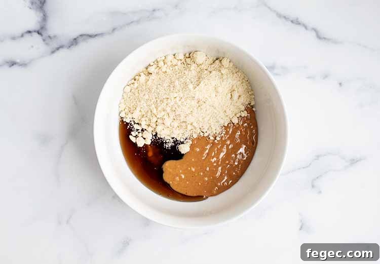white bowl with peanut butter, maple syrup, and coconut flour
