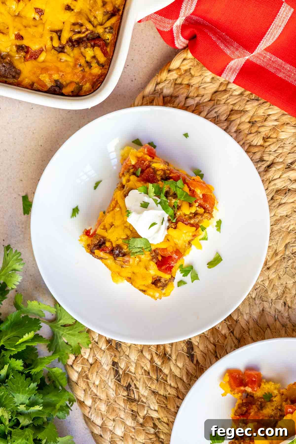 A serving of casserole is topped with a dollop of sour cream and some chopped fresh cilantro.