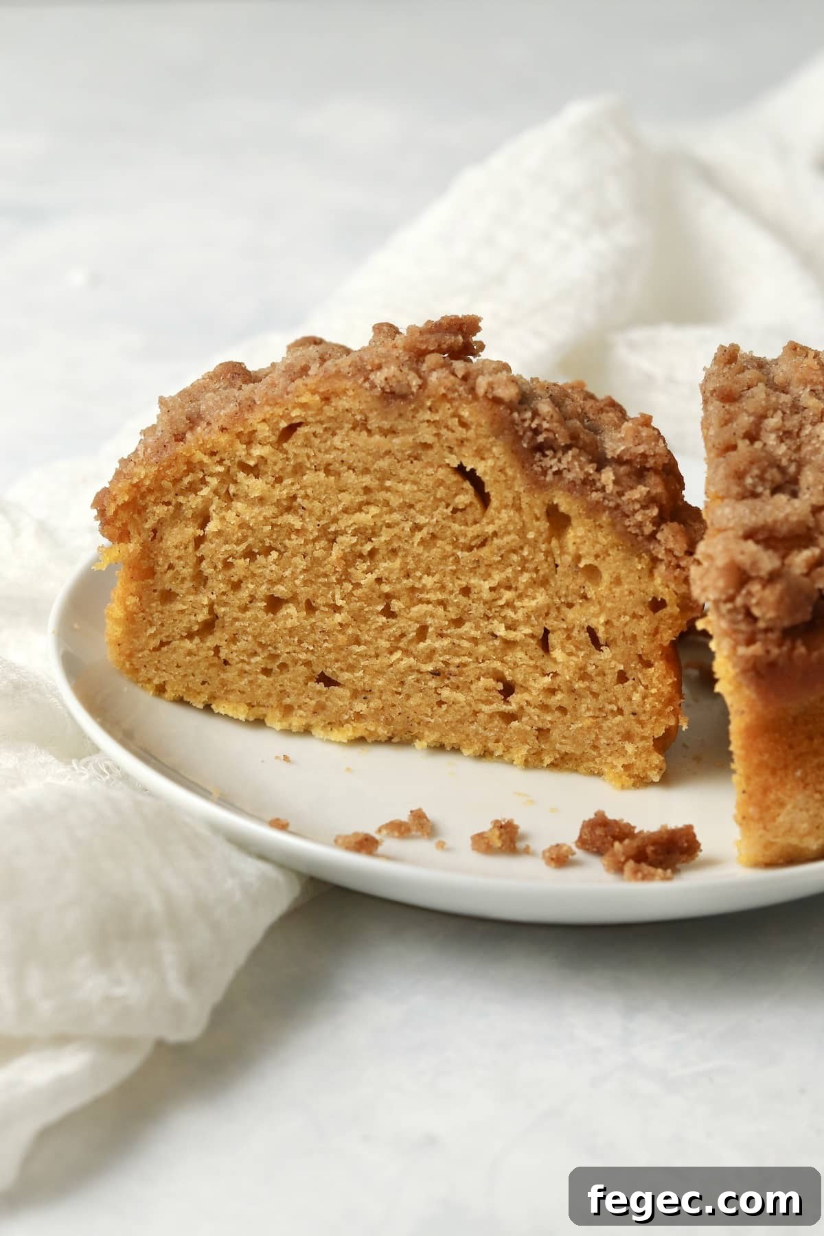 Single-Serve Pumpkin Coffee Cake Recipe (Small Batch) 2 Single serve pumpkin coffee cake with streusel topping cut in half on a plate.