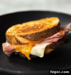 spatula lifting grilled cheese from pan with cheese dripping out