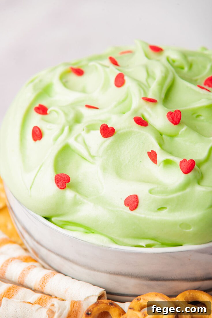 close up of grinch dip in a bowl surrounded by cookies