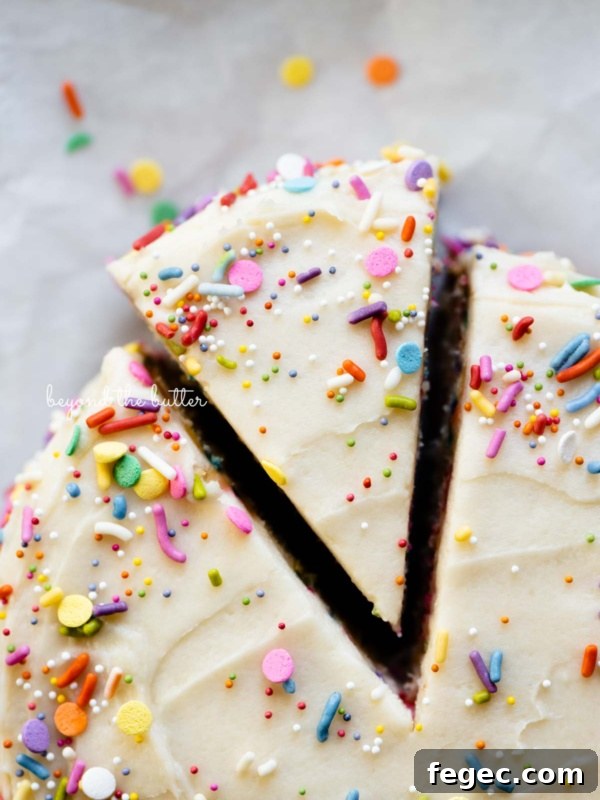 Cut slice of single layer funfetti cake partially removed from rest of the cake on white parchment paper.