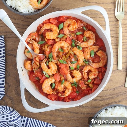 large white casserole dish of shrimp creole garnished with sliced green onions