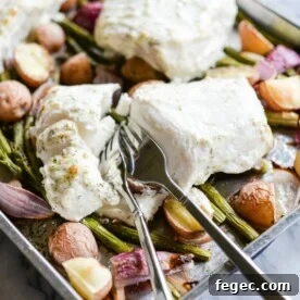 baked halibut filets on top of roasted potatoes, red onions, and asparagus on a sheet pan