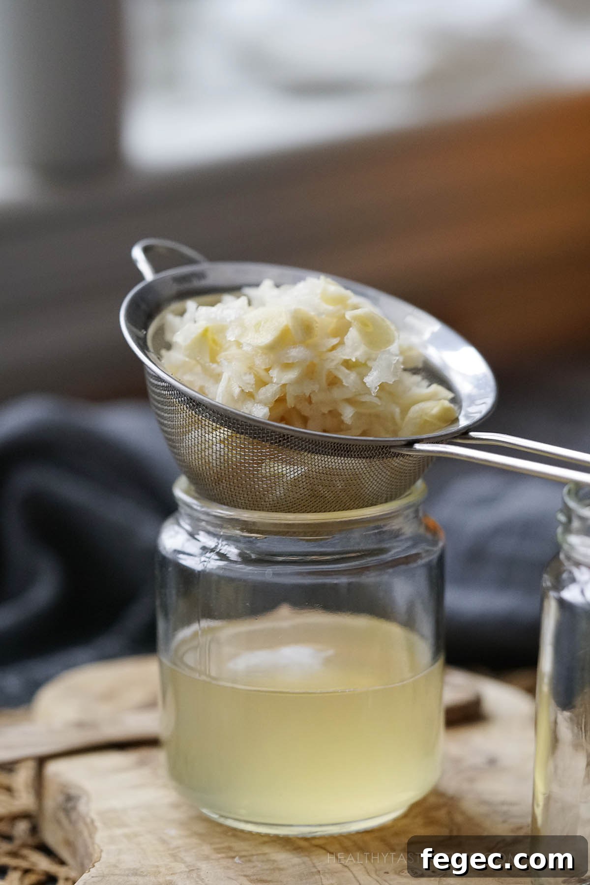Shot showing how to strain the homemade cough syrup into a jar.