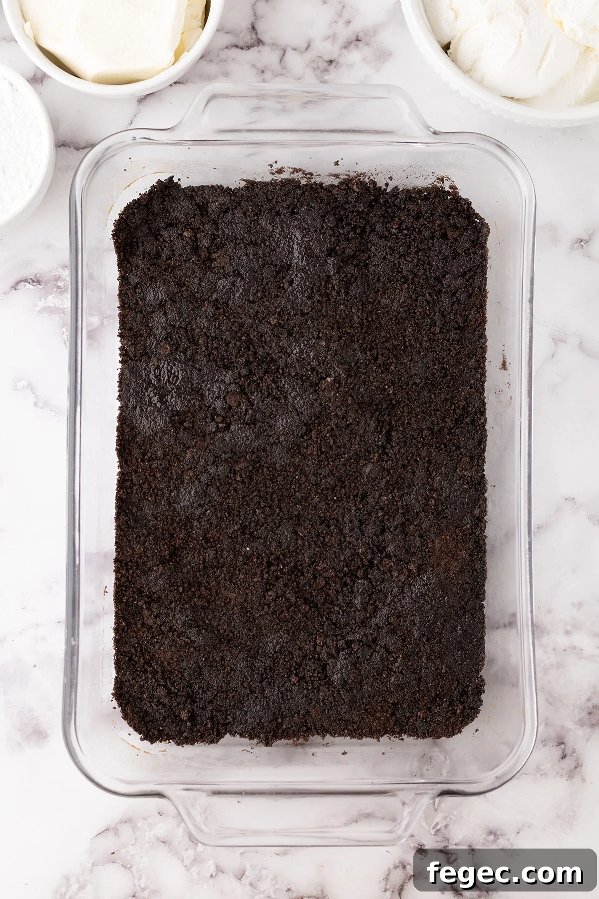 Crushed Oreos crust pressed into the bottom of a baking dish.
