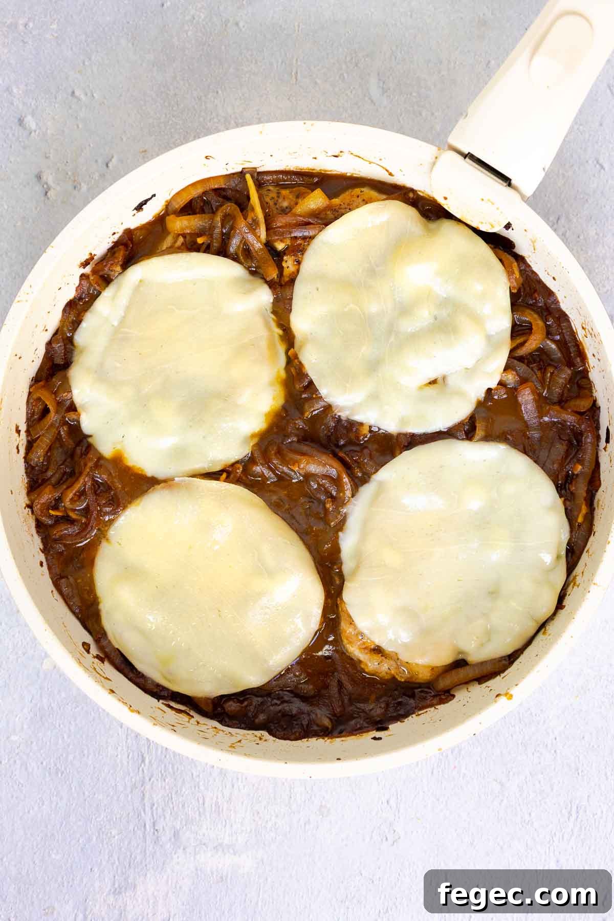 French Onion Pork Chops with Melted Gruyère and Caramelized Onions 12 Pork chops in a skillet topped with melted provolone over a bed of caramelized onions.