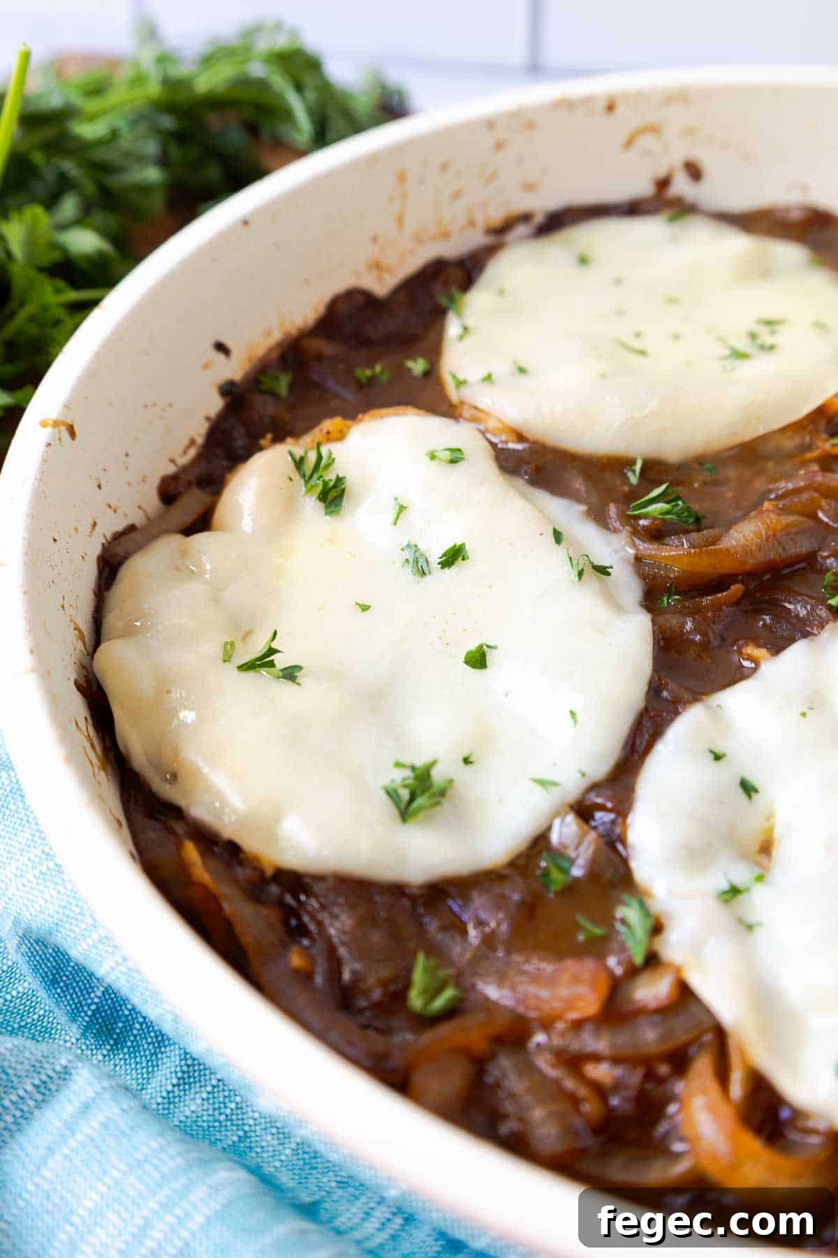 French Onion Pork Chops with Melted Gruyère and Caramelized Onions 13 Pork chops in a skillet topped with melted provolone and chopped parsley over caramelized onions.