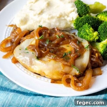 French Onion Pork Chops with Melted Gruyère and Caramelized Onions 17 A pork chop topped with provolone and onions on a plate with mashed potatoes and broccoli.
