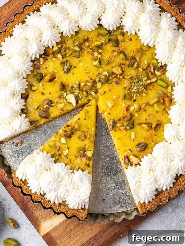 Lemon curd tart with pistachios decorated with piped whipped cream.