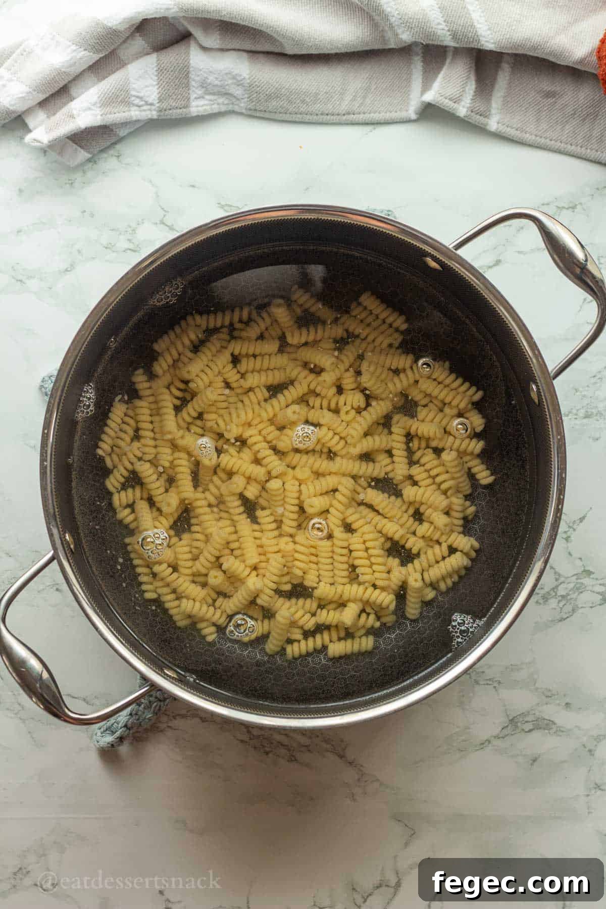 Uncooked pasta in pan with water.
