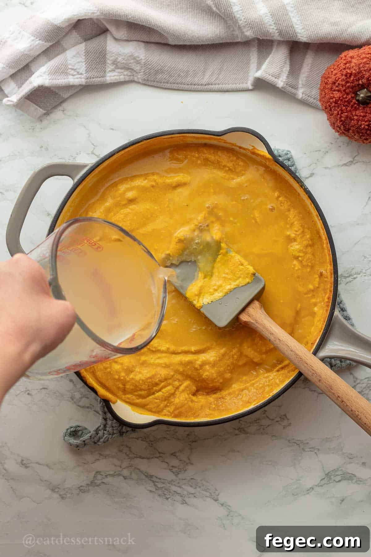Pouring pasta water into pan with pumpkin sauce.